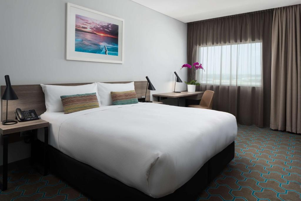 a hotel room with a large bed and a large window at Rydges Sydney Airport Hotel in Sydney
