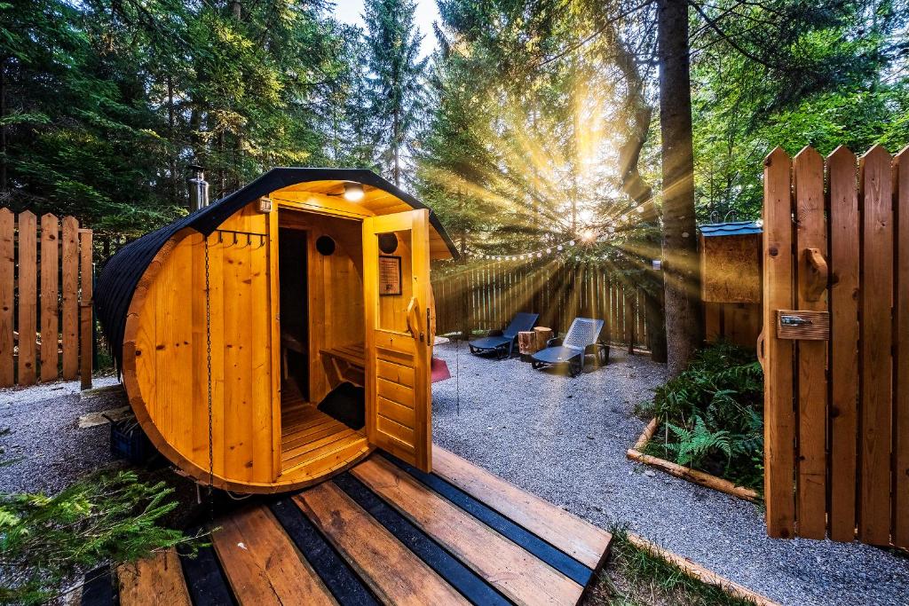 una pequeña cabaña de madera con el sol en el fondo en Glamping FOREST EDGE, en Kamnik