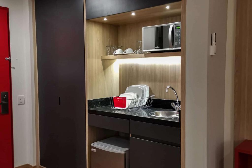 a kitchen with a sink and a microwave at Ramada Encore by Wyndham Guadalajara Aeropuerto in Guadalajara