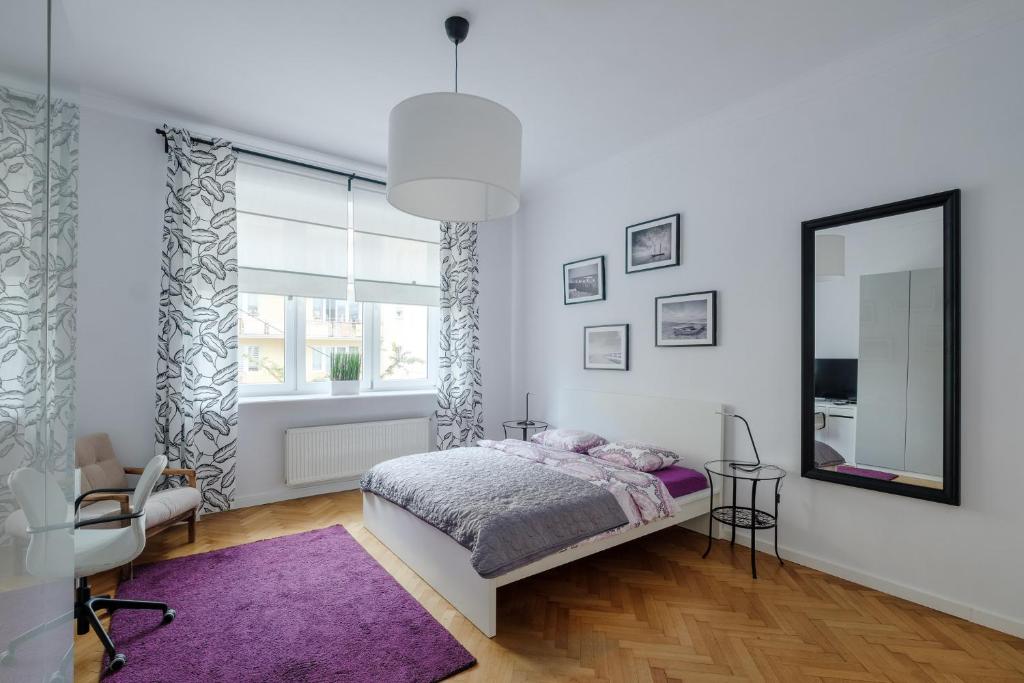 um quarto com uma cama, um espelho e uma janela em Apartamenty Starowiejska 37 em Gdynia