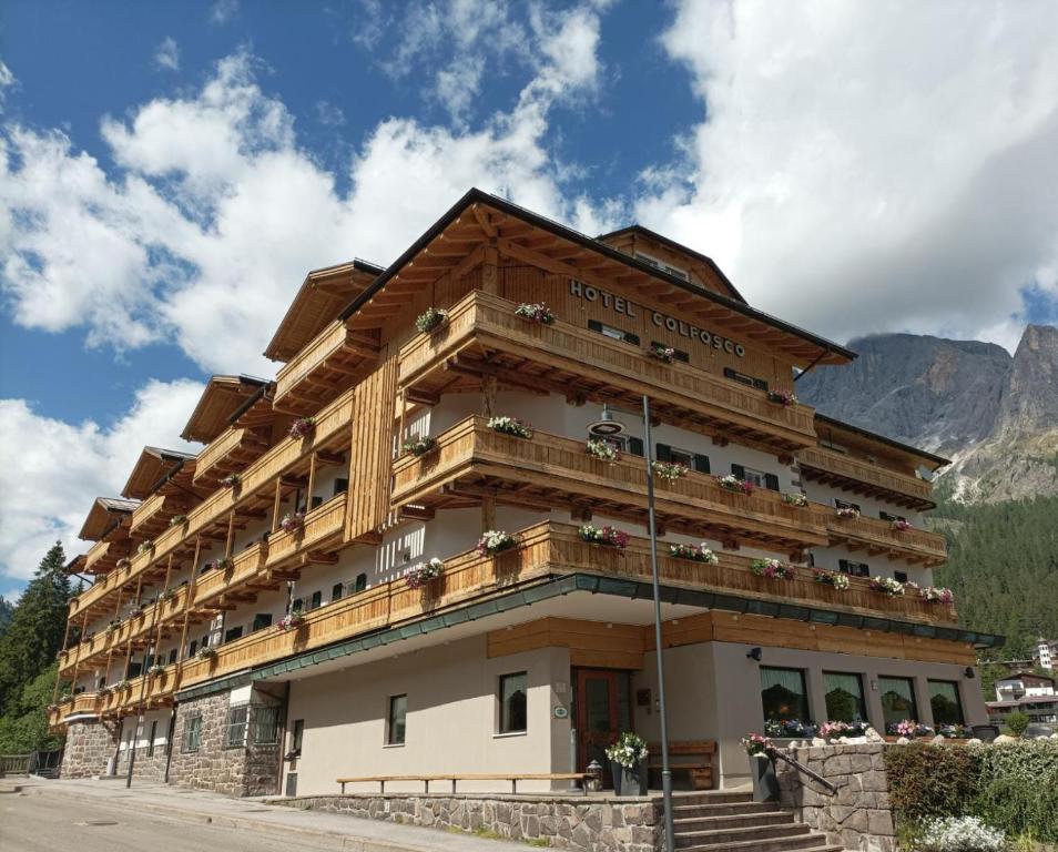 a hotel building with a mountain in the background at Hotel Colfosco in San Martino di Castrozza