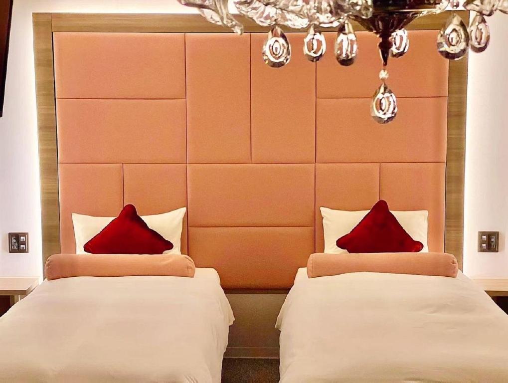 two beds in a hotel room with red pillows at Doutonbori Crystal Hotel in Osaka