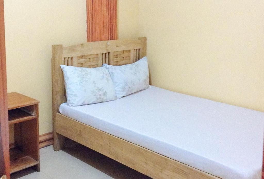 a bed with a wooden headboard and a pillow at RedDoorz Hostel @ Baguio Tourist Cabin in Baguio