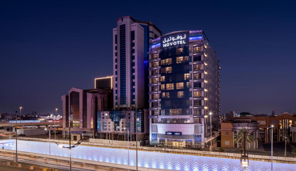 un edificio alto con un cartel en él por la noche en Novotel Jeddah Tahlia en Yeda