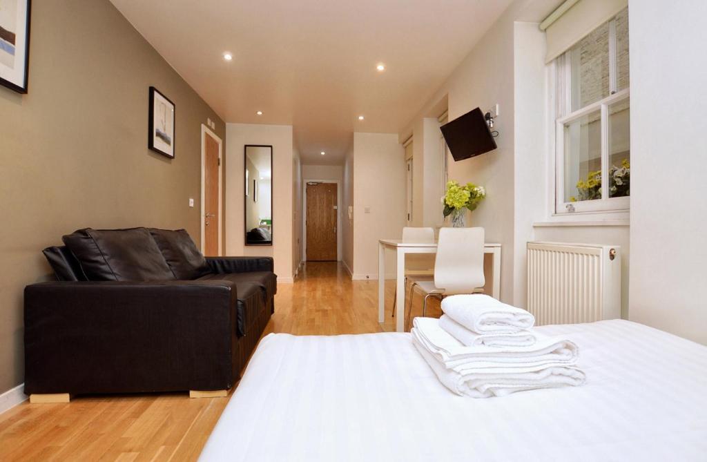 ein Schlafzimmer mit einem Bett, einem Sofa und einem Tisch in der Unterkunft Concept Serviced Apartments by Concept Apartments in London