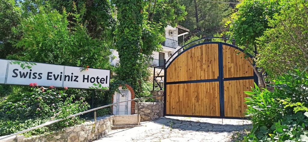 a wooden gate with a sign in front of it at Swiss Eviniz Hotel - Adult Hotel in Adrasan