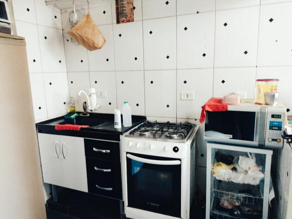 a kitchen with a stove and a microwave at Hostel Dona Lucia in São José dos Campos