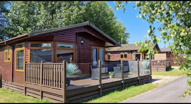 eine Blockhütte mit einer Terrasse und einem Haus in der Unterkunft Lakeside 18 in Warton