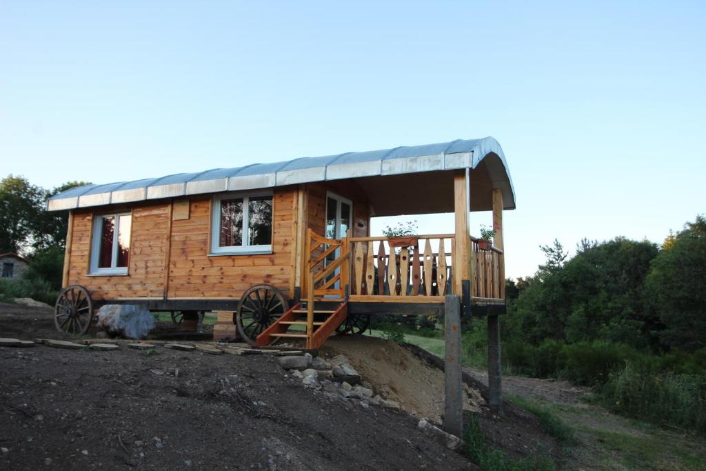 a small wooden cabin with a metal roof at roulotte impériale perchée- in Sembadel