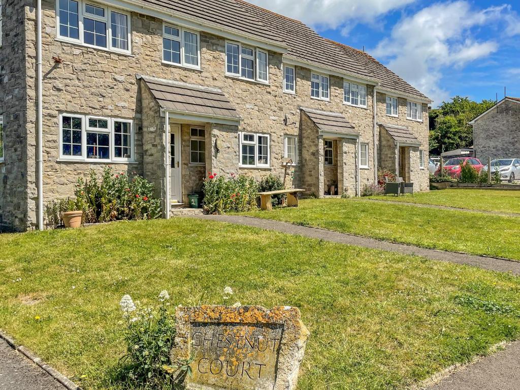 a stone house with a court sign in front of it at West Lulworth Apartment in Wareham