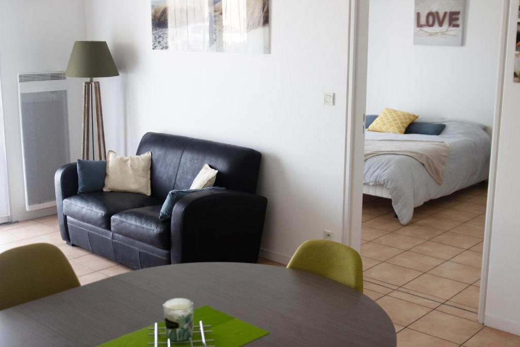 un soggiorno con divano in pelle nera e tavolo di Villa Saint Fort - Résidence Services a Saint-Fort