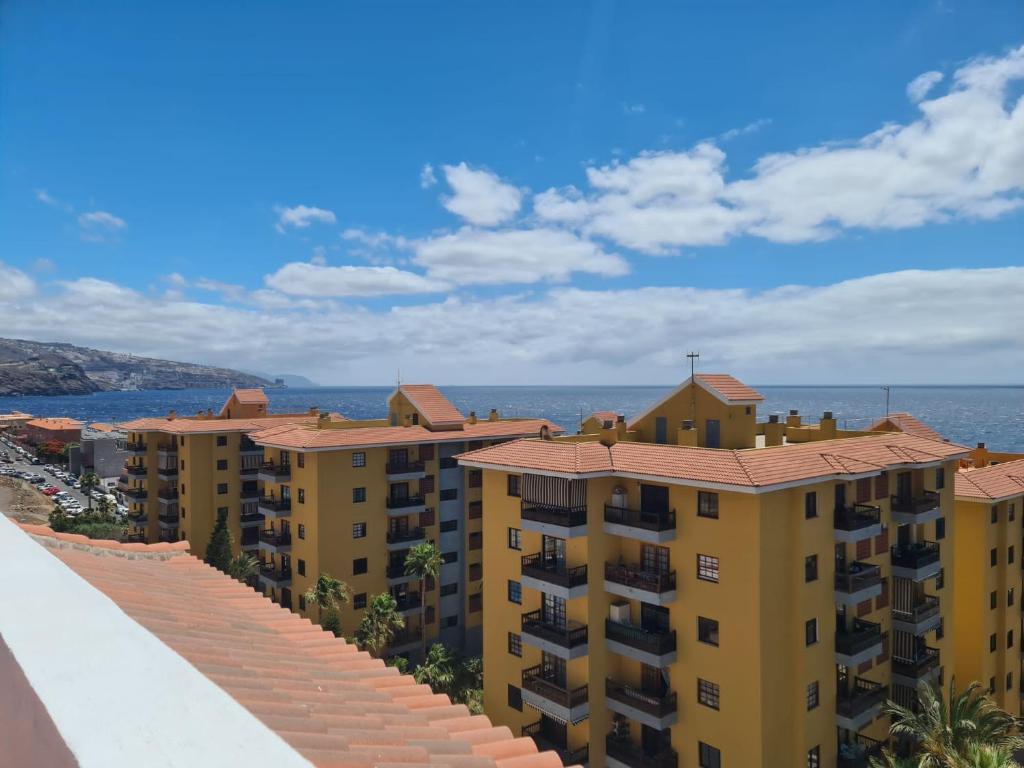a row of yellow apartment buildings next to the ocean at CAROLINA SUITE APARTMENT in Candelaria