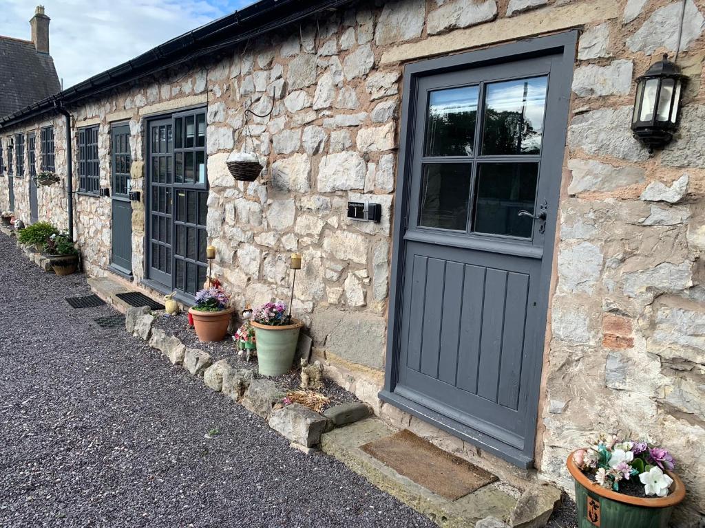 a stone building with a door and some potted plants at Dwylig Isa Holiday Cottages in Rhuddlan