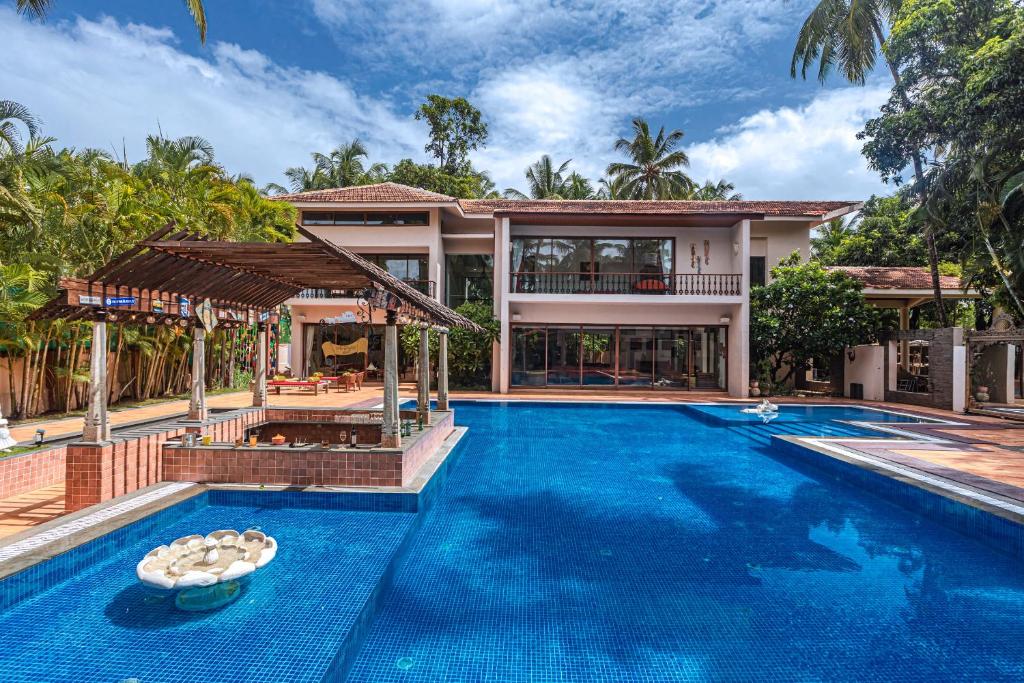 an exterior view of a villa with a swimming pool at Saffronstays Casa Del Palms, Alibaug - luxury pool villa with chic interiors, alfresco dining and island bar in Alibaug