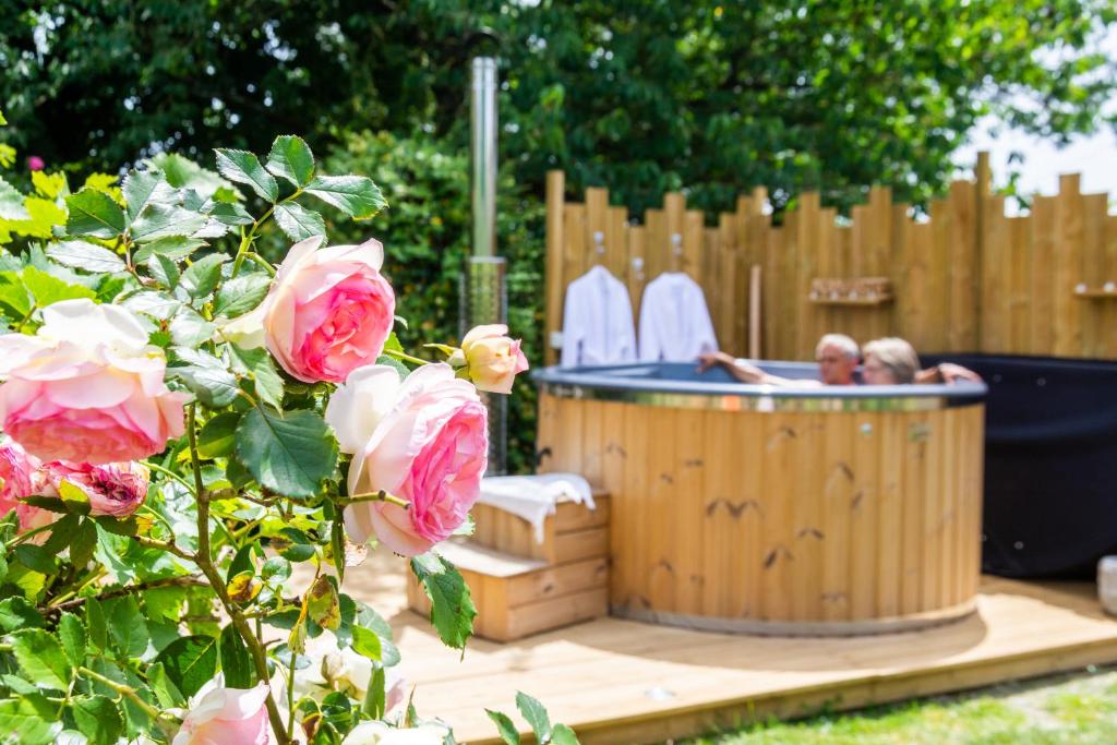 a man and a woman in a hot tub in a yard at Cabane en bois avec bain nordique in Asnières-sur-Vègre