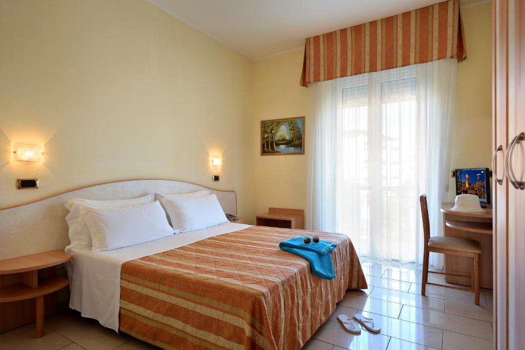 a bedroom with a bed and a table and a window at Hotel Elisir in Rimini