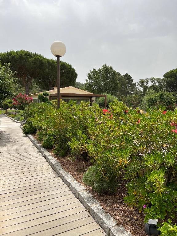 une passerelle en bois avec des fleurs devant un bâtiment dans l'établissement Les Jardins De Santa Giulia - Charmante chambre dhte 2, à Porto-Vecchio