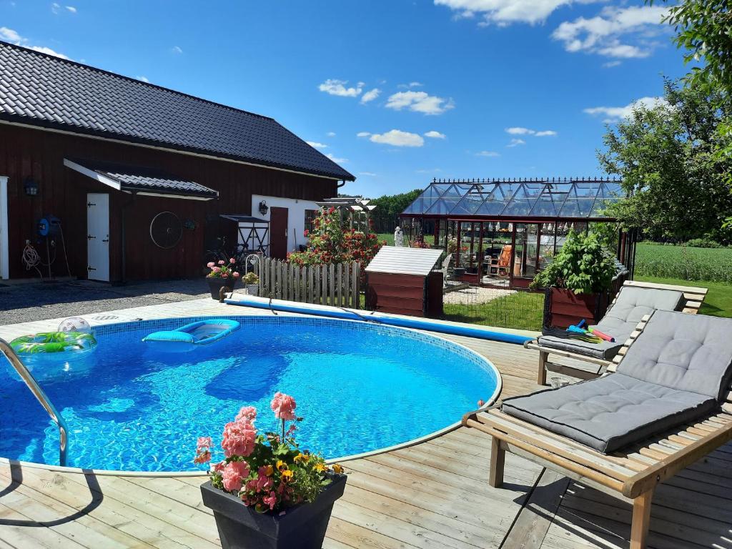 una gran piscina en una terraza de madera con un banco y una silla en Gårdslägenhet nära Göteborg, 