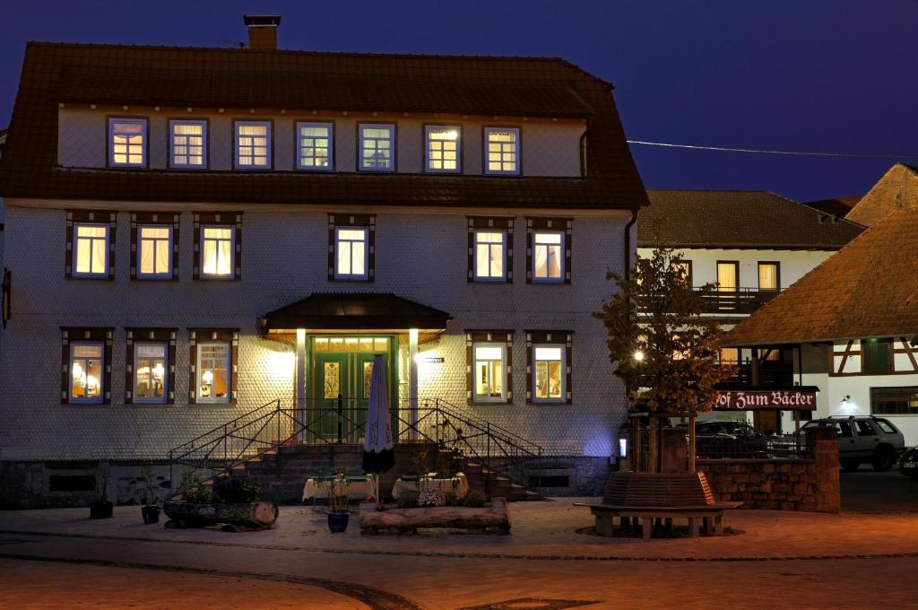 een groot wit gebouw met verlichting aan bij Hotel Zum Bäcker in Udenhain