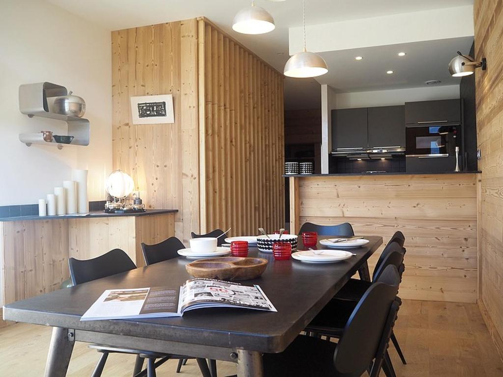 une table de salle à manger avec des chaises et une cuisine dans l'établissement DUPLEX rénové · 8 pers · Pied des pistes · 2 balcons · Wifi - FR-1-344-427, aux Menuires