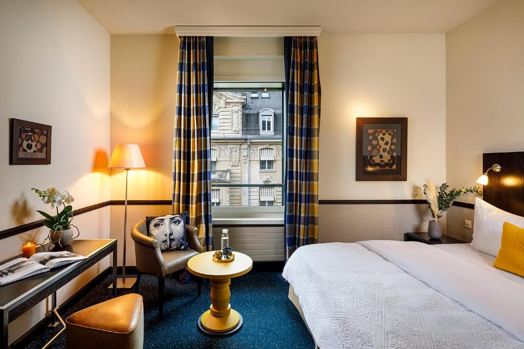 a hotel room with a bed and a chair and a window at Opera Hotel Zürich in Zürich