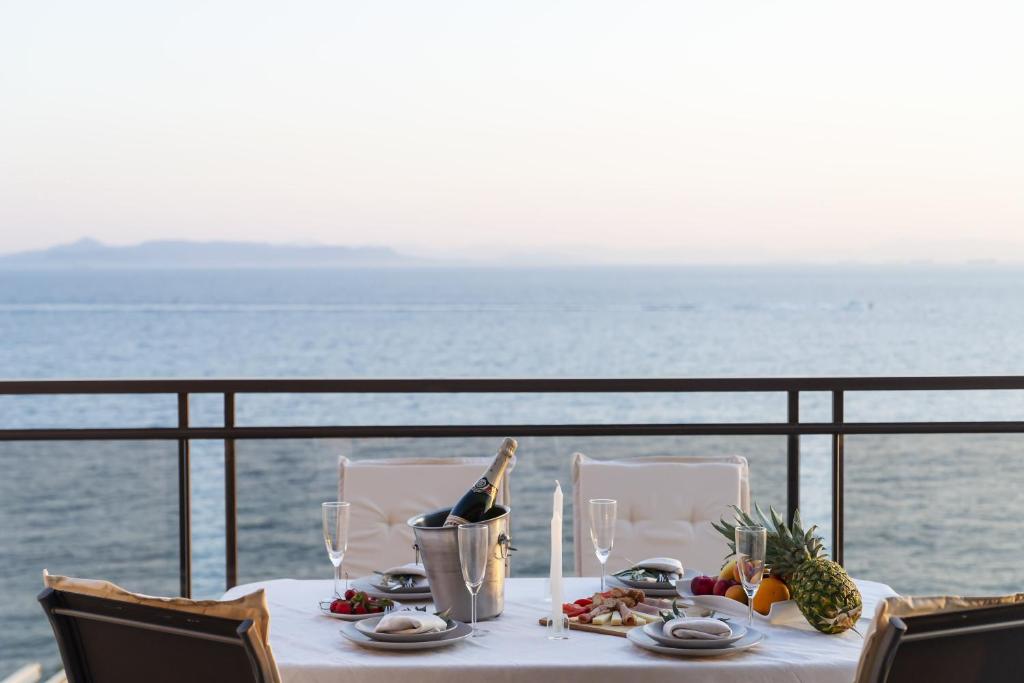 stół z jedzeniem i winem na balkonie z widokiem na ocean w obiekcie Blue Dreams - Spectacular Sea View Apartment in Athens w Atenach