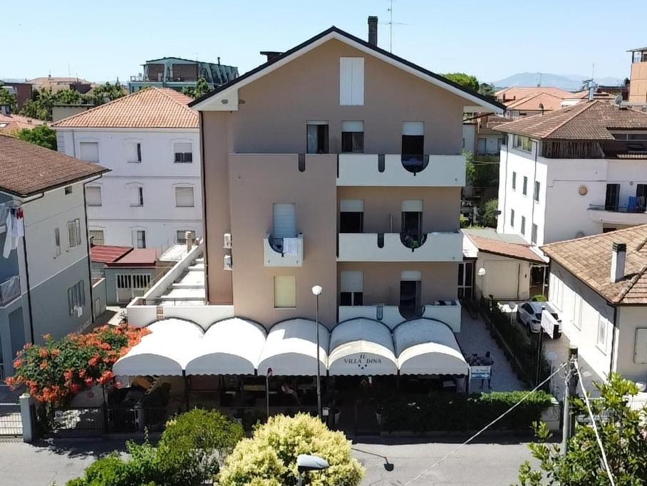a building with white awnings in a city at Hotel Villa Dina in Rimini