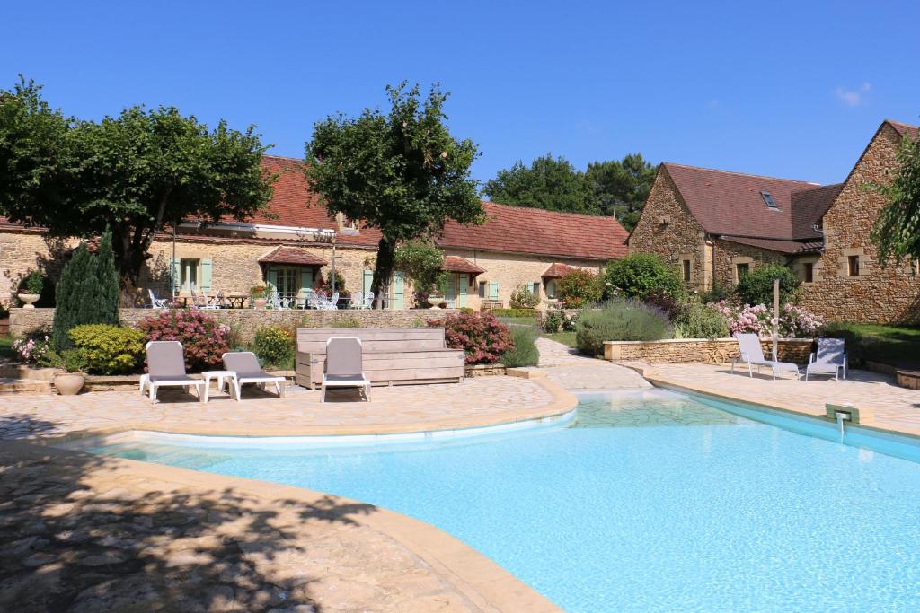 einen Pool in einem Garten mit Stühlen und einem Haus in der Unterkunft Hôtel de la Ferme Lamy in Meyrals