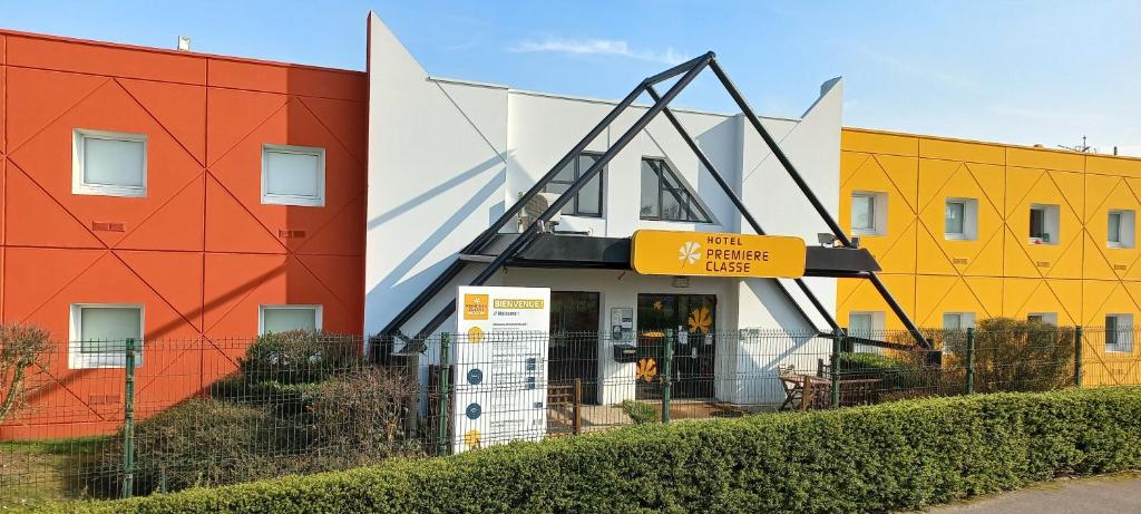 un bâtiment avec des bâtiments colorés à côté d'une clôture dans l'établissement Premiere Classe Arras - Tilloy Les Mofflaine, à Tilloy-lès-Mofflaines