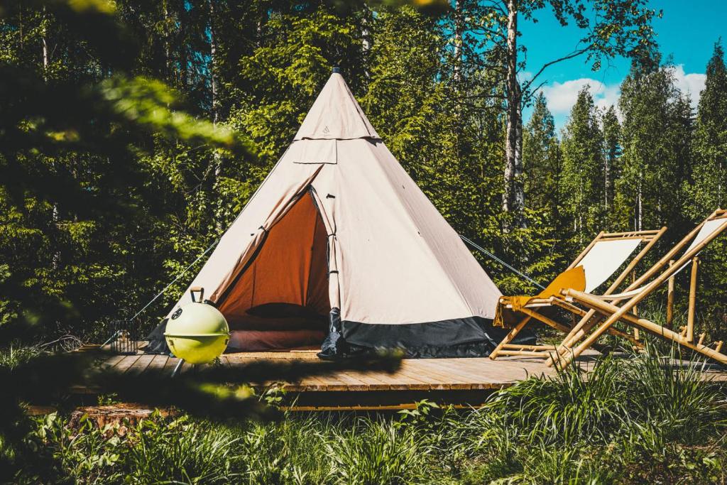 a white and orange teepee tent in a field at Venejoen Piilo - Loimu in Kontiolahti