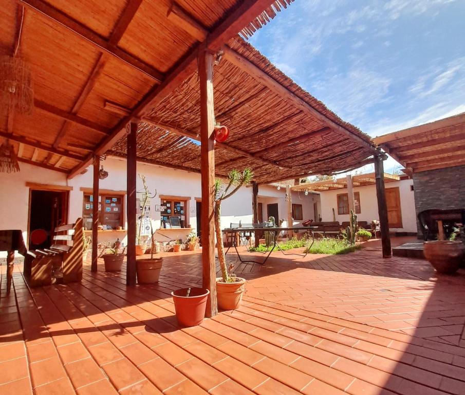 a patio with a wooden roof with potted plants at La Casa del Pueblo Hostal in San Pedro de Atacama