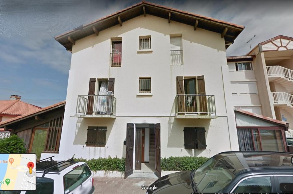 a white building with cars parked in front of it at Appartement 4 personnes Vieux-Boucau in Vieux-Boucau-les-Bains