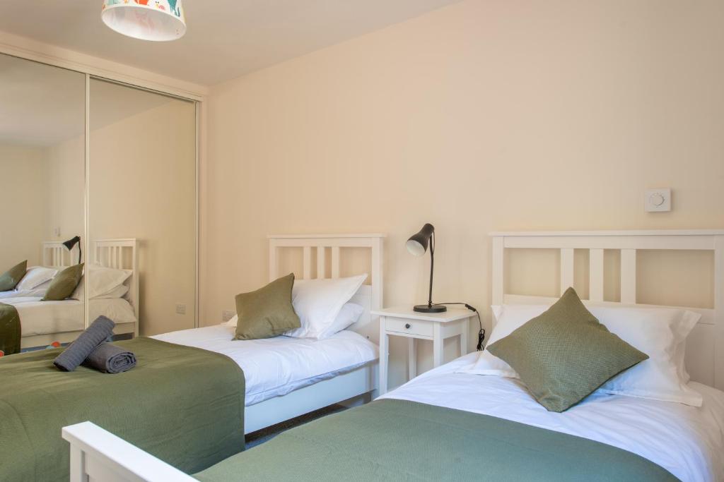 a bedroom with two beds and a mirror at Modern, well placed house walkable to beach & town in Lyme Regis