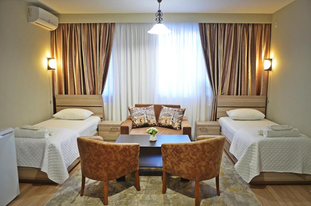 a hotel room with two beds and a table and chairs at Apartment Paysage in Tbilisi City