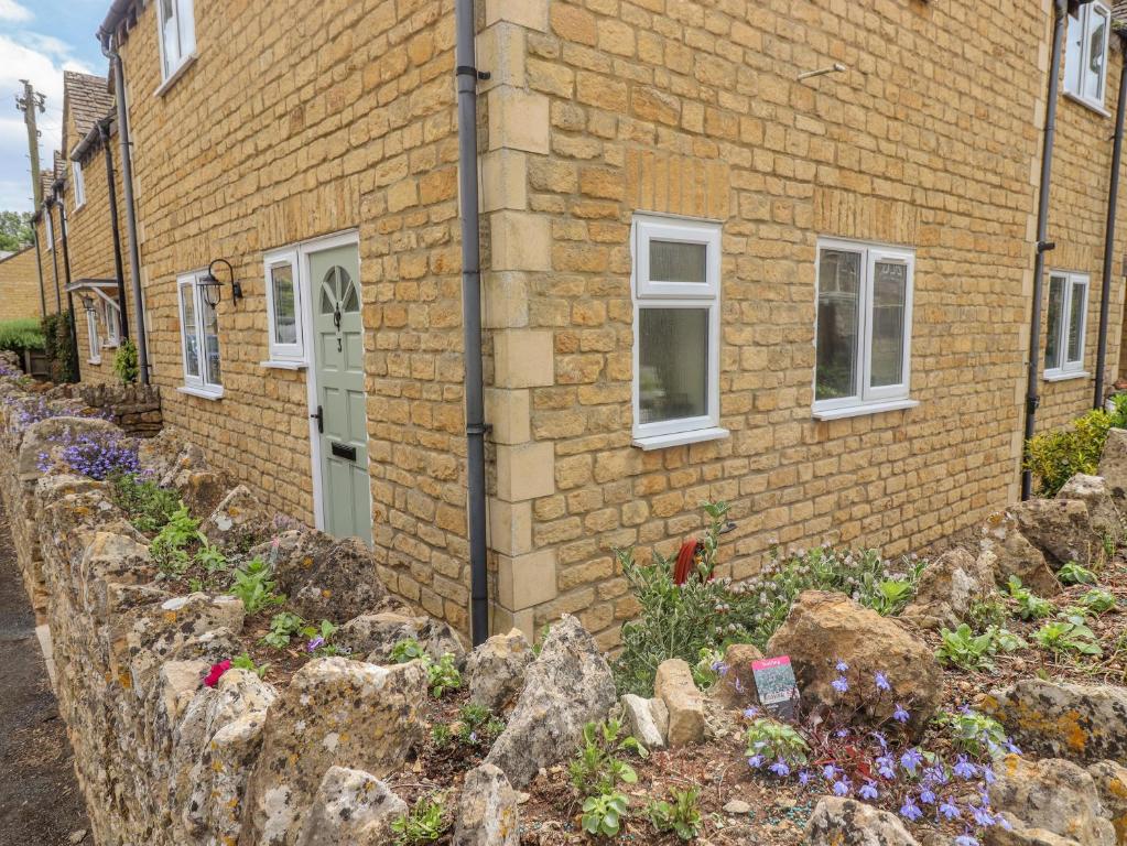 a brick house with a retaining wall and flowers at The Cornerstone in Cheltenham