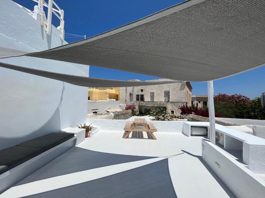a patio with a table under a large umbrella at Cycladic Rooftop House in the Heart of Parikia in Parikia