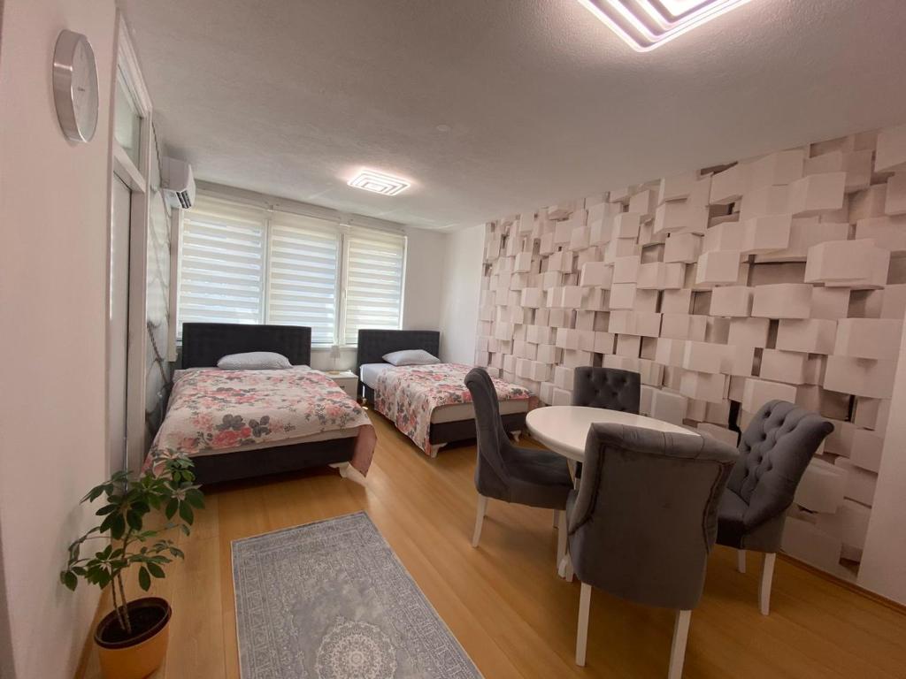 een kamer met 2 bedden en een tafel en stoelen bij Apartman Citylux in Bihać