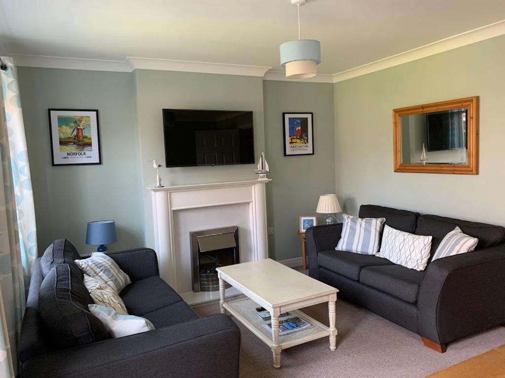 a living room with two couches and a fireplace at Merchant House Snettisham in Kings Lynn