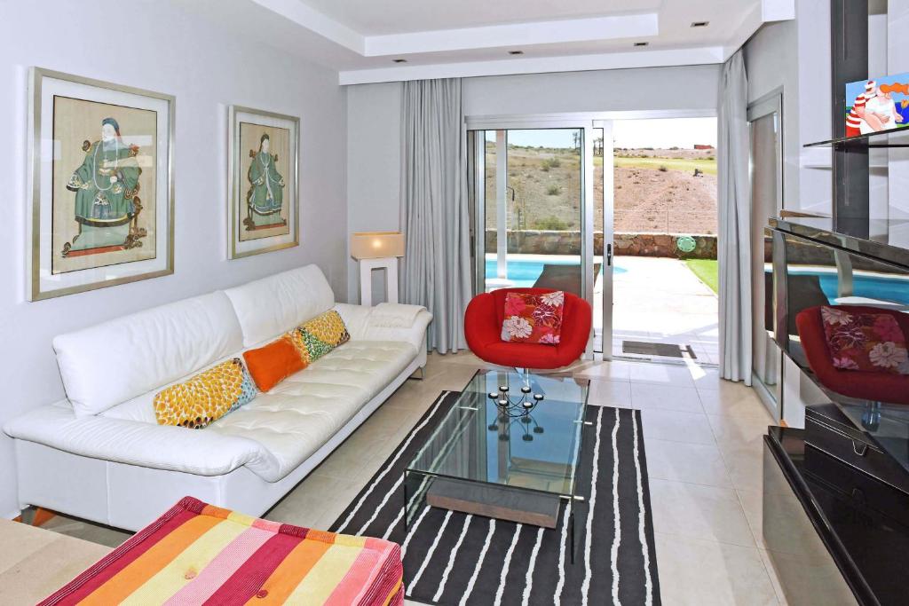 salon z białą kanapą i czerwonym krzesłem w obiekcie Salobre Vista Golf 26 w mieście Maspalomas