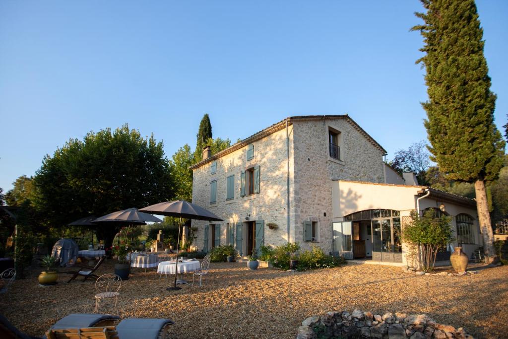 un bâtiment avec des parasols et des tables devant lui dans l'établissement Le Mas des Romarins, à Fayence