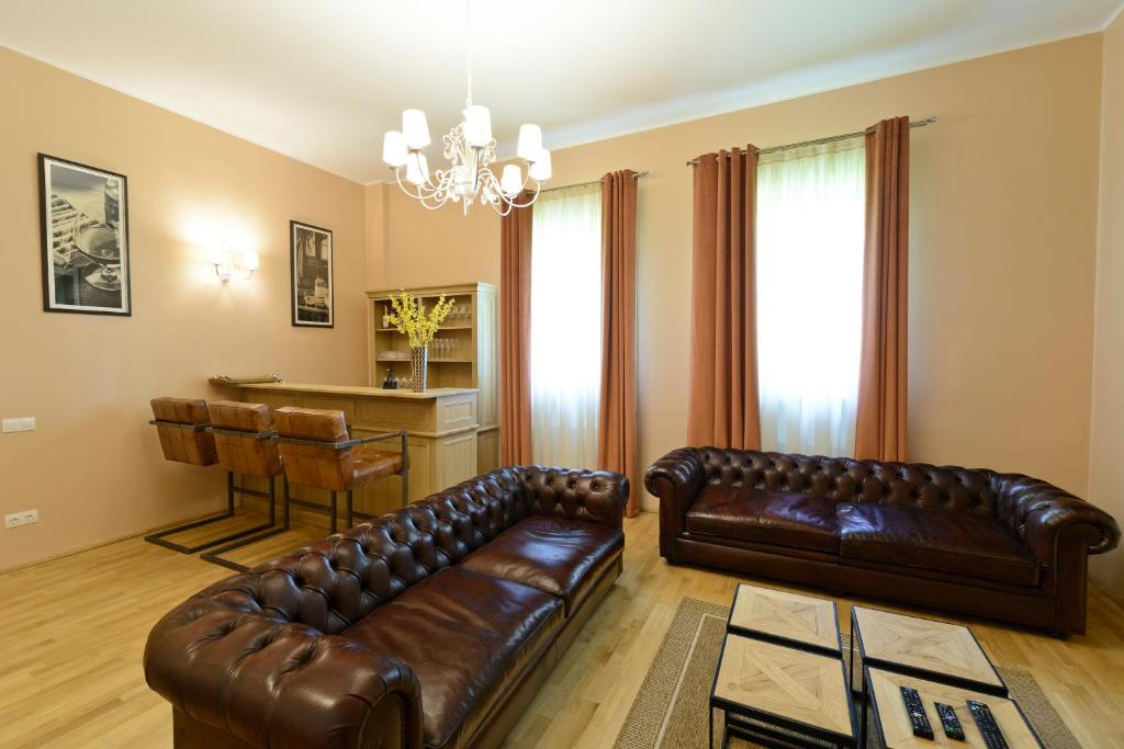 una sala de estar con 2 sofás de cuero y una mesa. en Pensiunea Elphin en Târgu Mureș