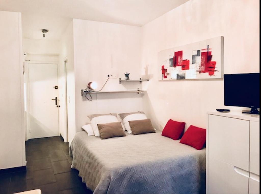 a white bedroom with a bed with red pillows at Studio Croisette Palais des Festivals in Cannes