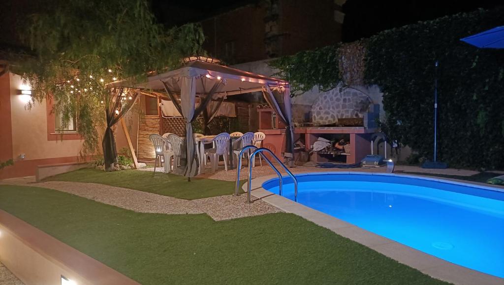 una piscina en un patio trasero por la noche en Maison Belle Époque & suites, en Oristano