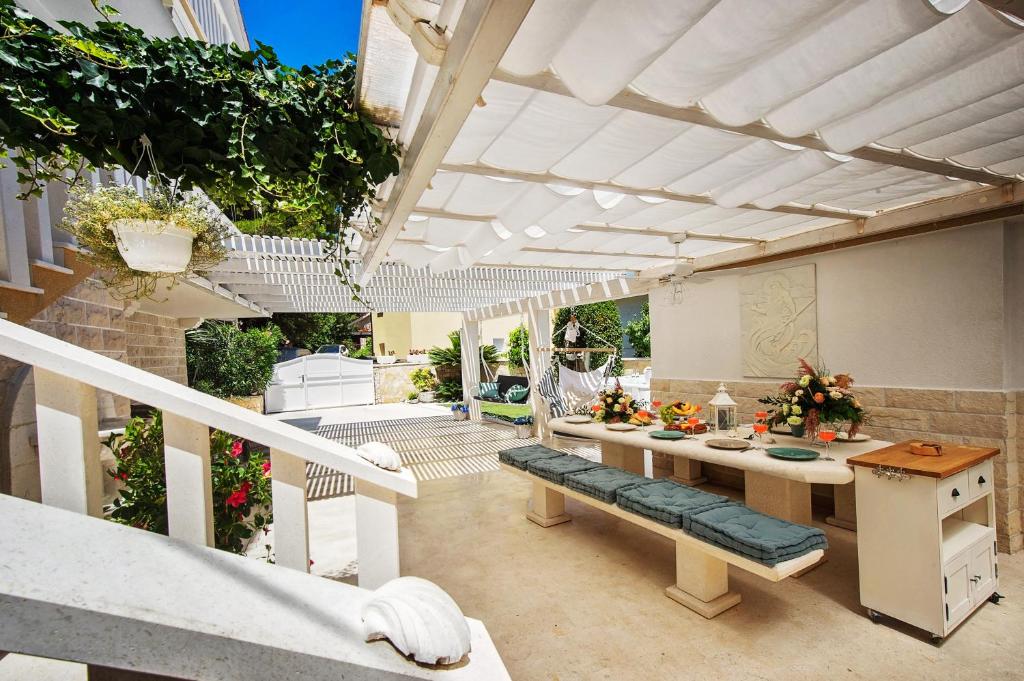 a patio with a bench and a table with flowers at Casa del Mare in Rogoznica