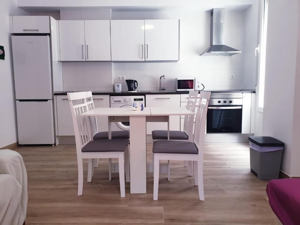 a white kitchen with a white table and chairs at Premier Apartments in Valencia