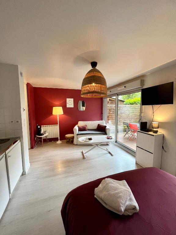 1 dormitorio con cama y pared roja en Cassis - Studio terrasse - Centre Dijon BSB Jouvence, en Dijon