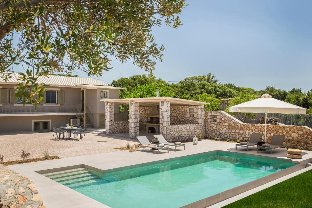 a backyard with a swimming pool and an umbrella at Villa Ktima in Argostoli