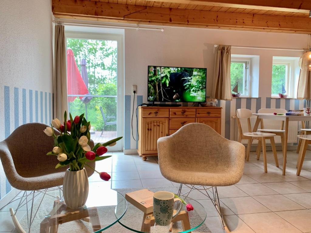 a living room with two chairs and a tv at Ferienwohnung 4 im Böhler Haubarg in Sankt Peter-Ording
