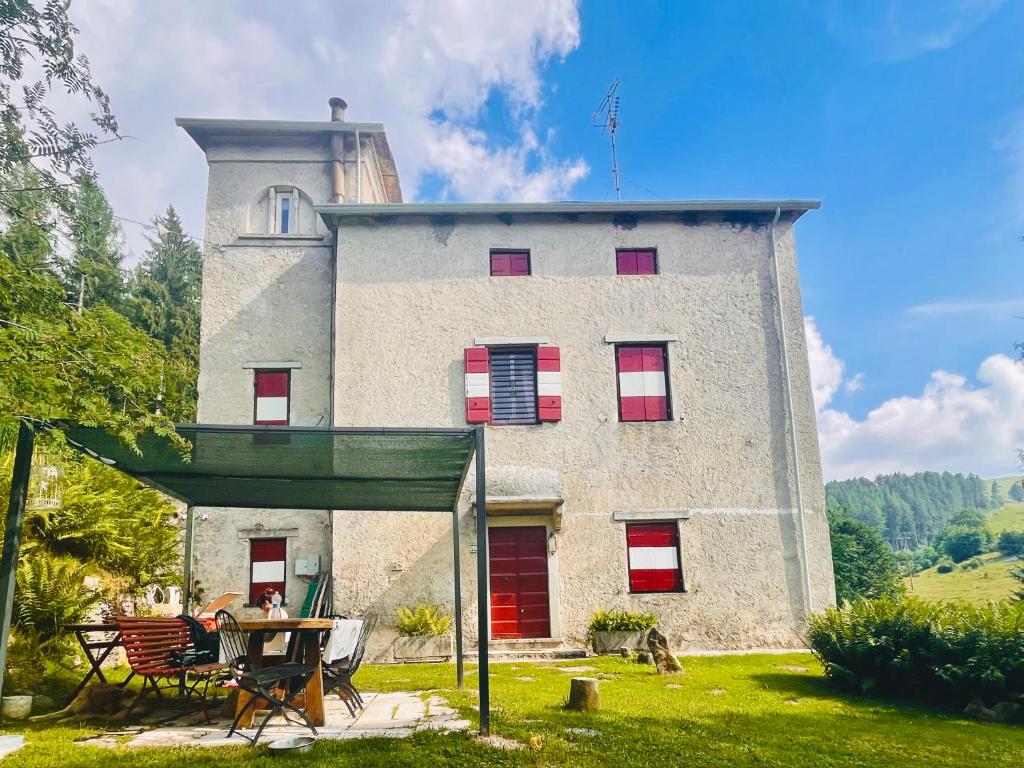 a building with red shutters and a table in front of it at Dimora Storica Lessinia in Ala
