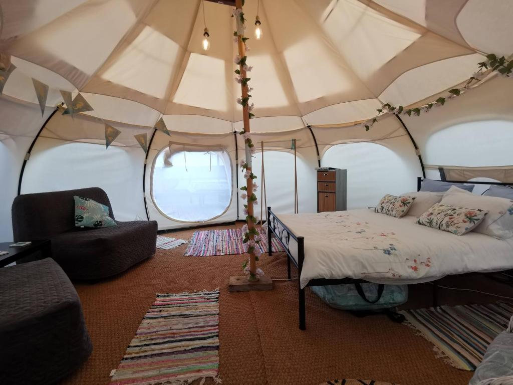 Pierrefiche的住宿－Glamping La Petite Lande，帐篷内的卧室,配有一张床和椅子